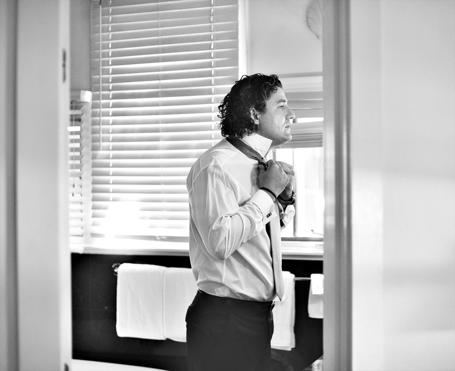 black and white photo of groom getting ready