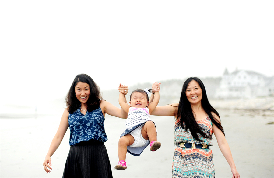 sisters swinging a baby on the beach