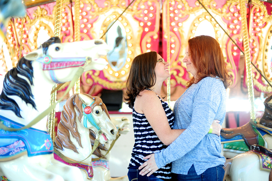 engagement photo in front of a carousel