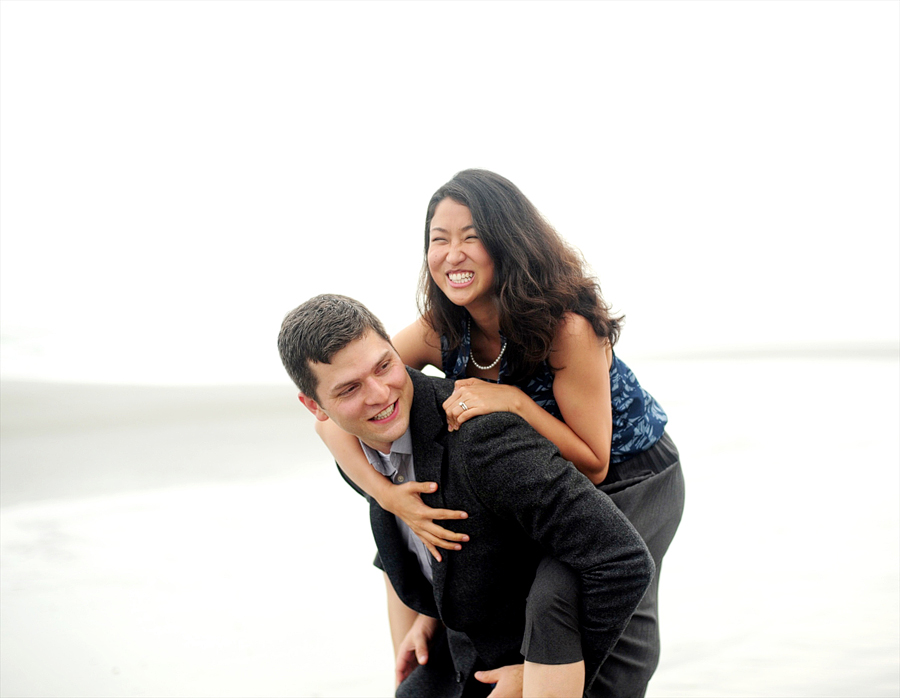 man giving his wife a piggyback ride on the beach