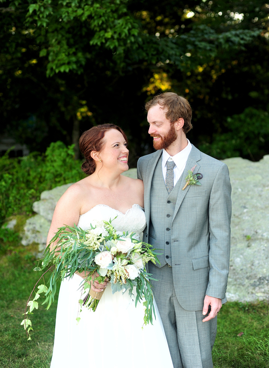 groom in a grey suit with his redhead bride