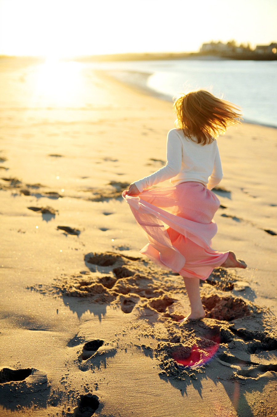 girl twirling at the beach at sunset