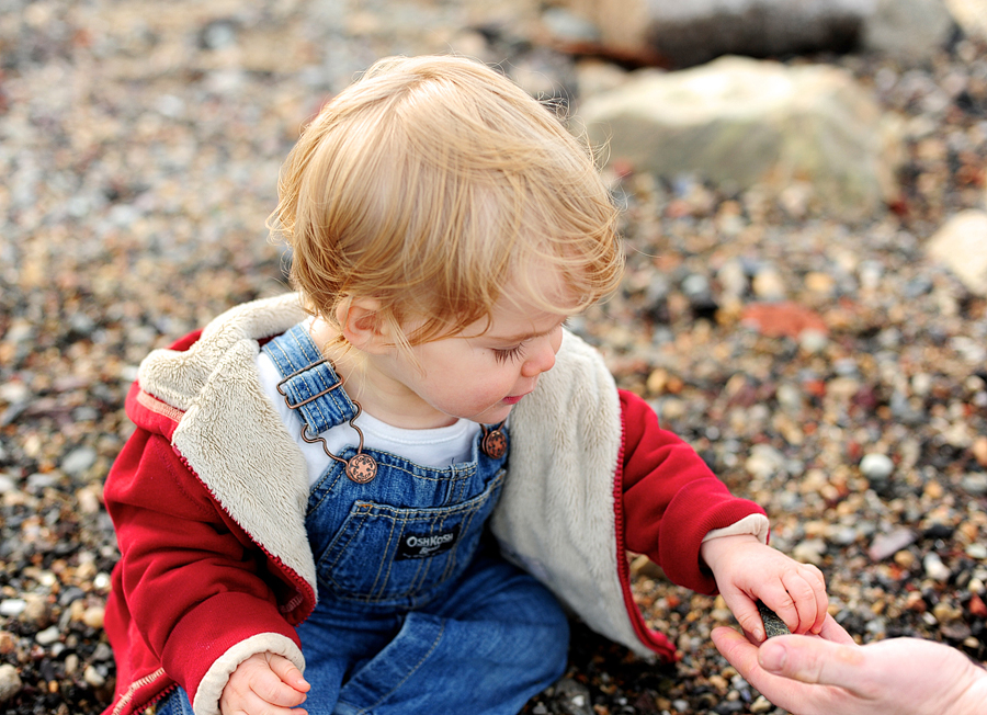 baby holding rocks on beach