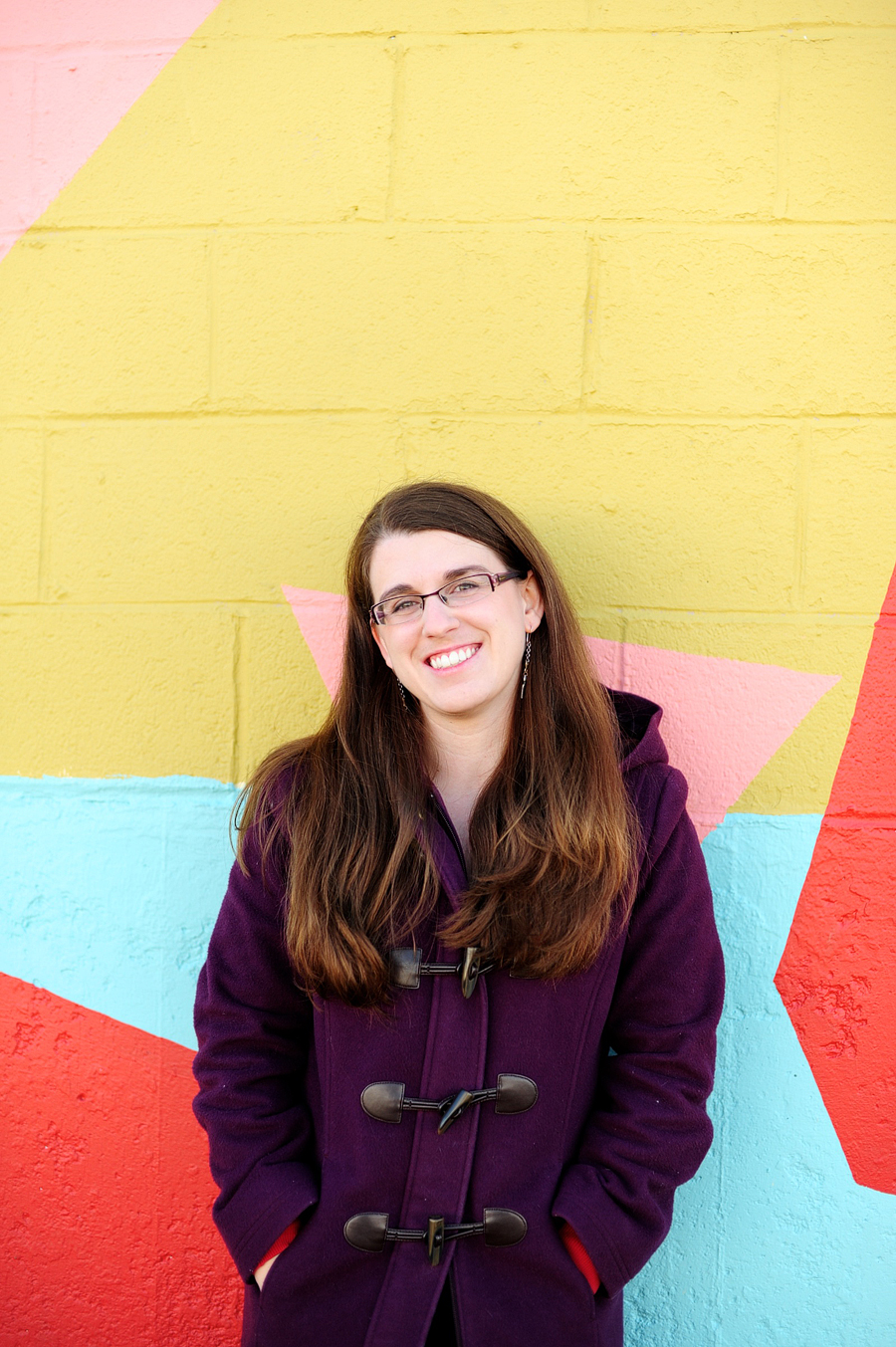 woman smiling in front of mural