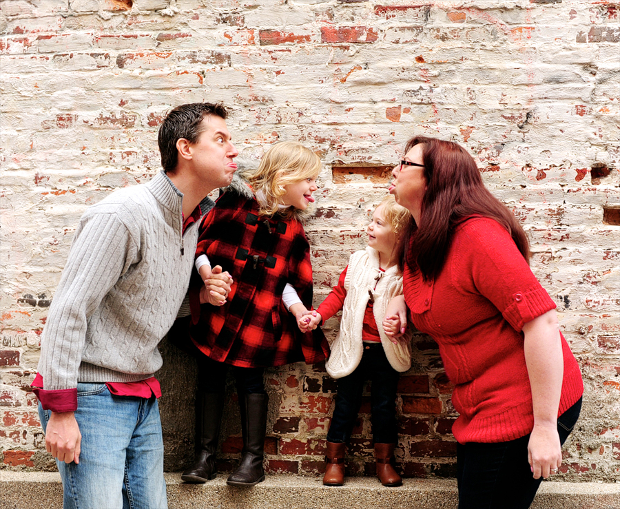 family goofing around in front of brick wall