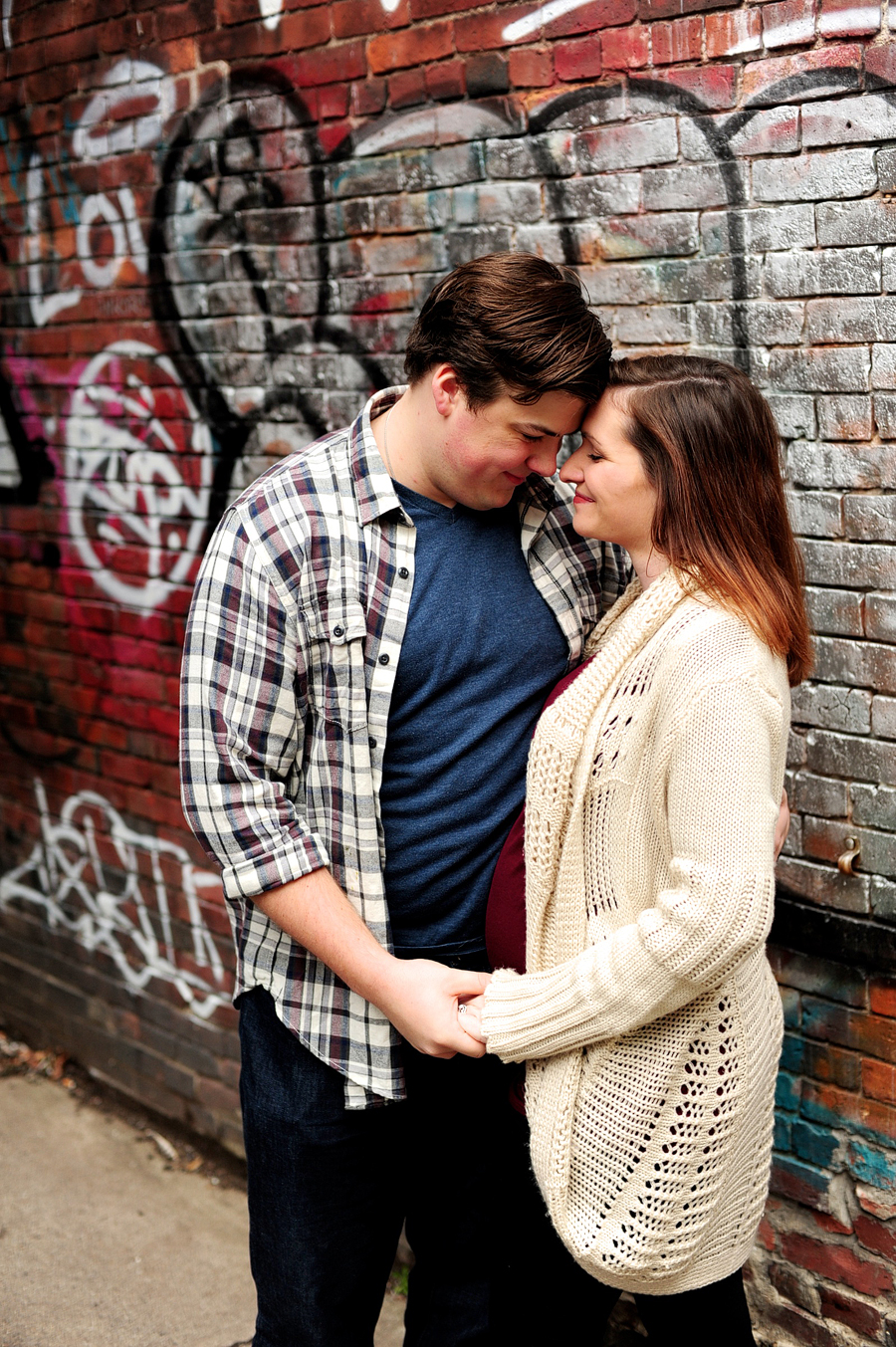 pregnant woman and husband smile near graffiti