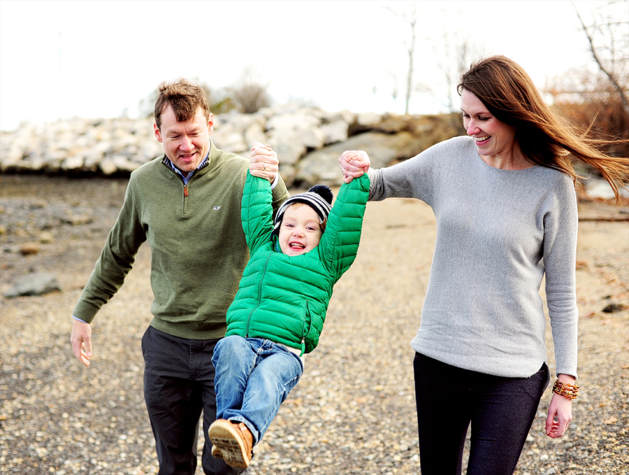 family with son in green jacket playing on beach