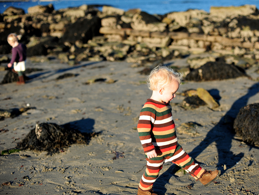kid in striped jumpsuit walking on beach