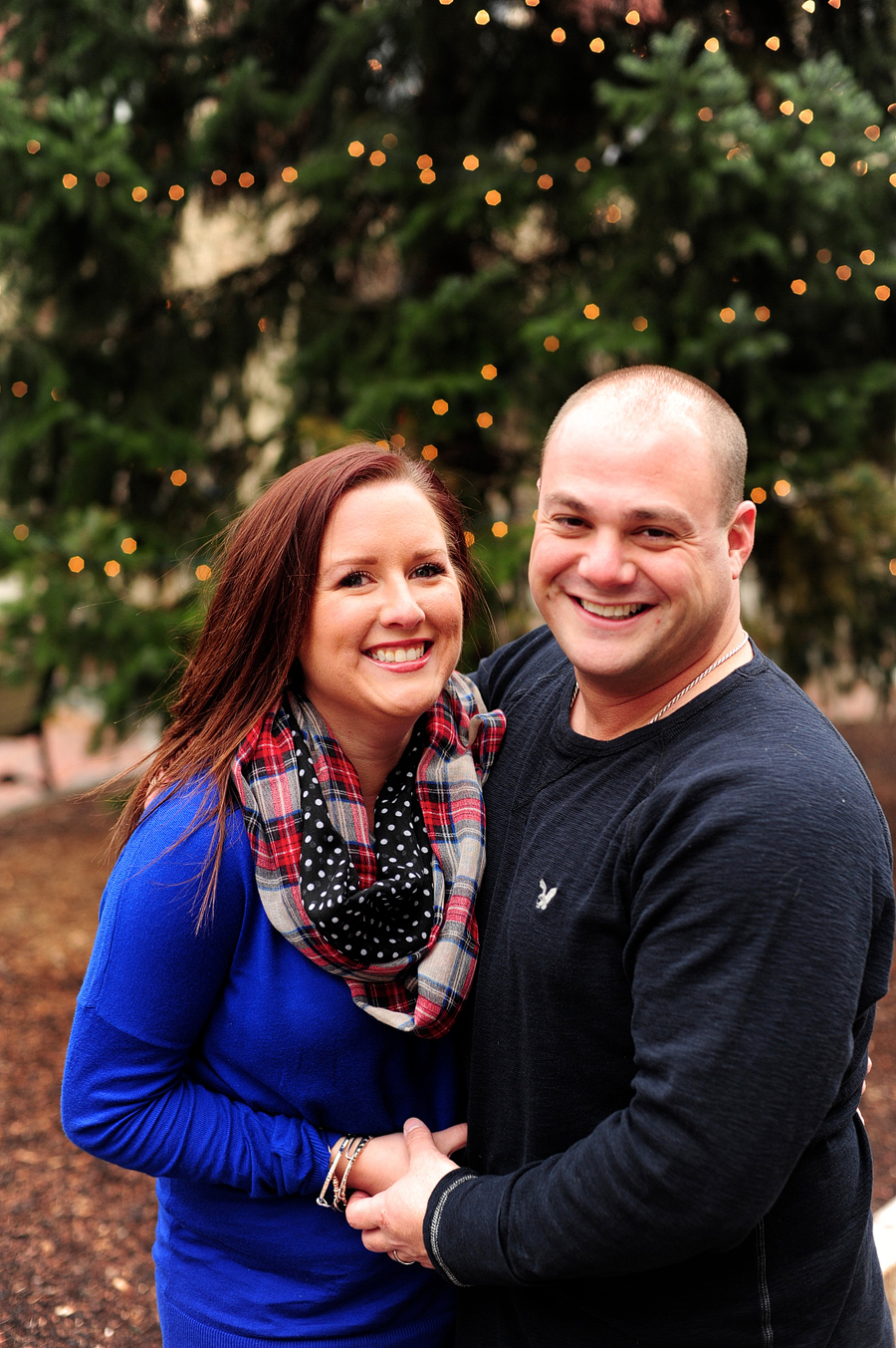 couple smiling in front of pine tree