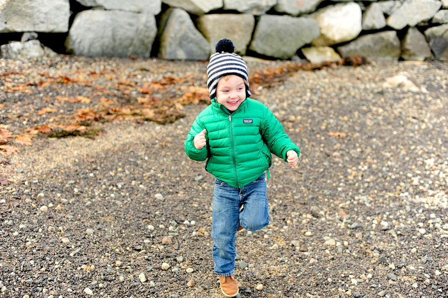 boy in winter coat and hat on beach in maine
