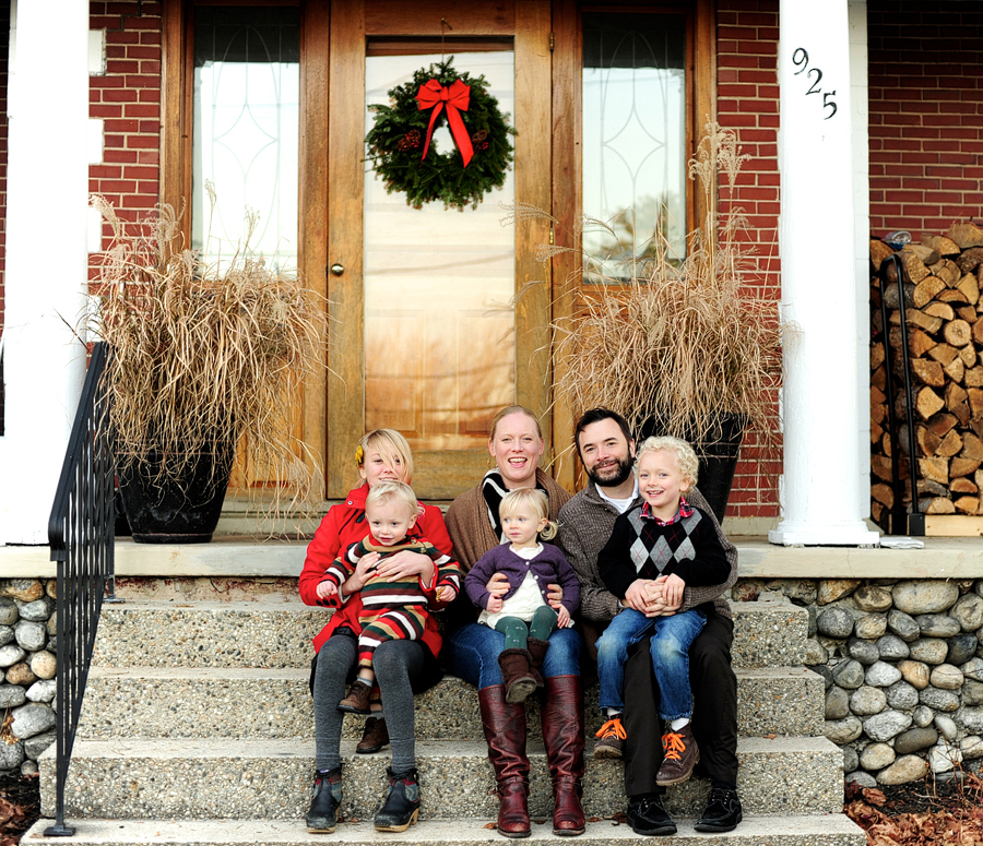 family posing on front steps of their house