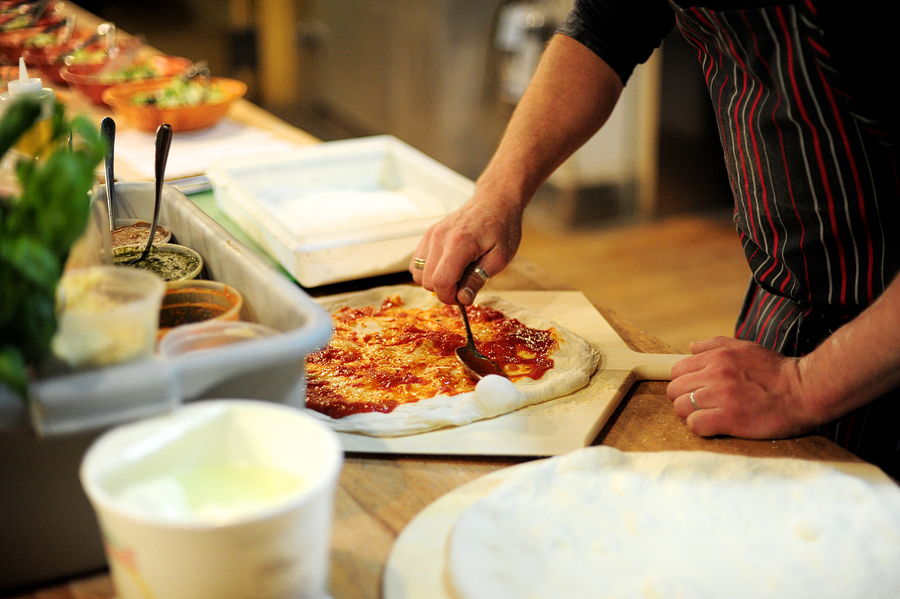 spreading pizza sauce on dough