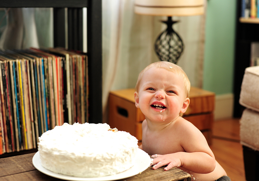 baby smiling next to cake
