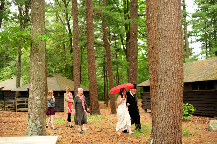 bride walking through the woods with a red umbrella