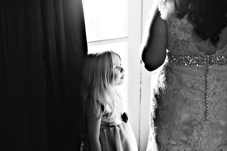 young daughter watching her bride mother get ready