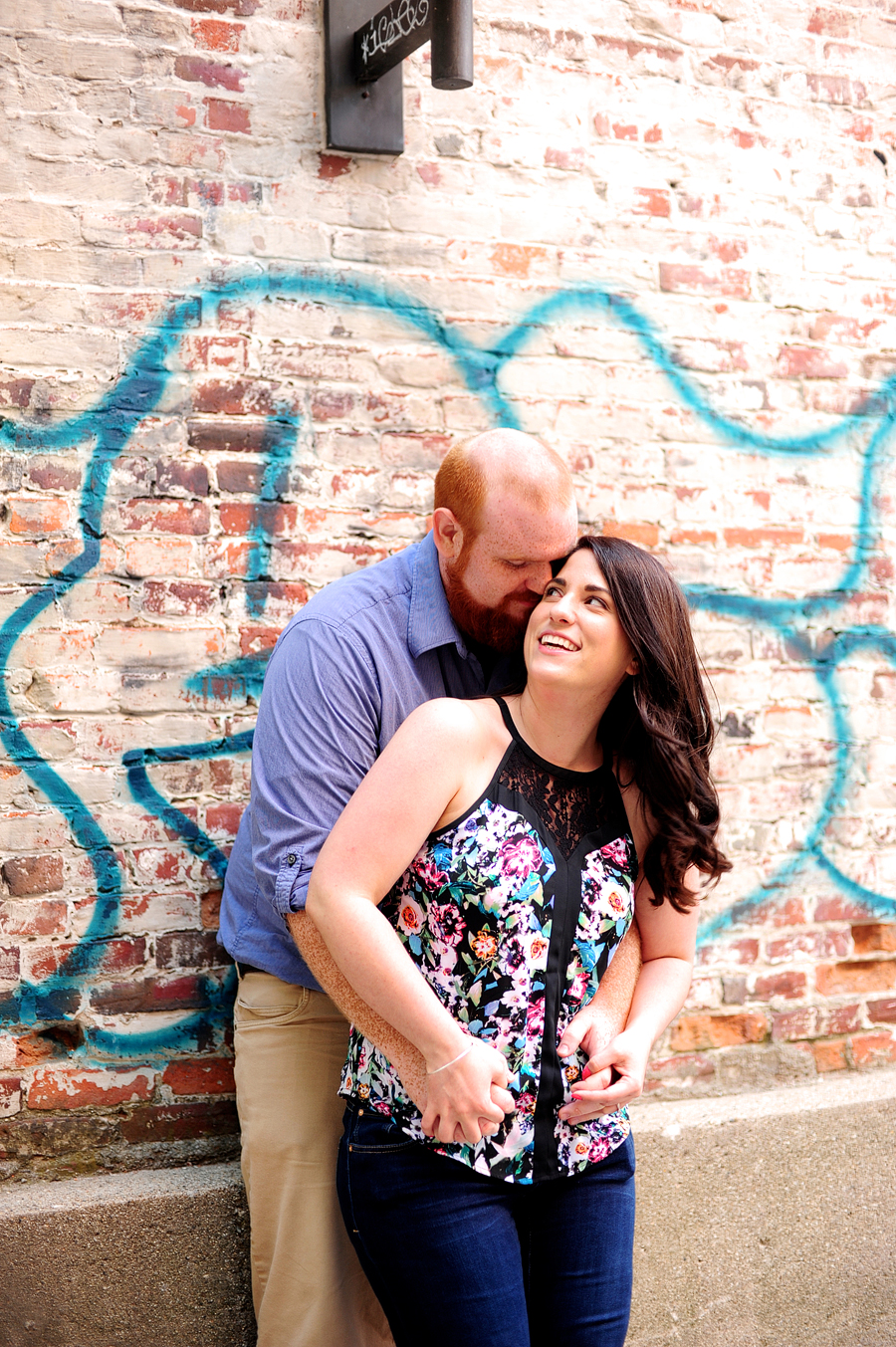 engagement photos in front of a brick wall with graffiti
