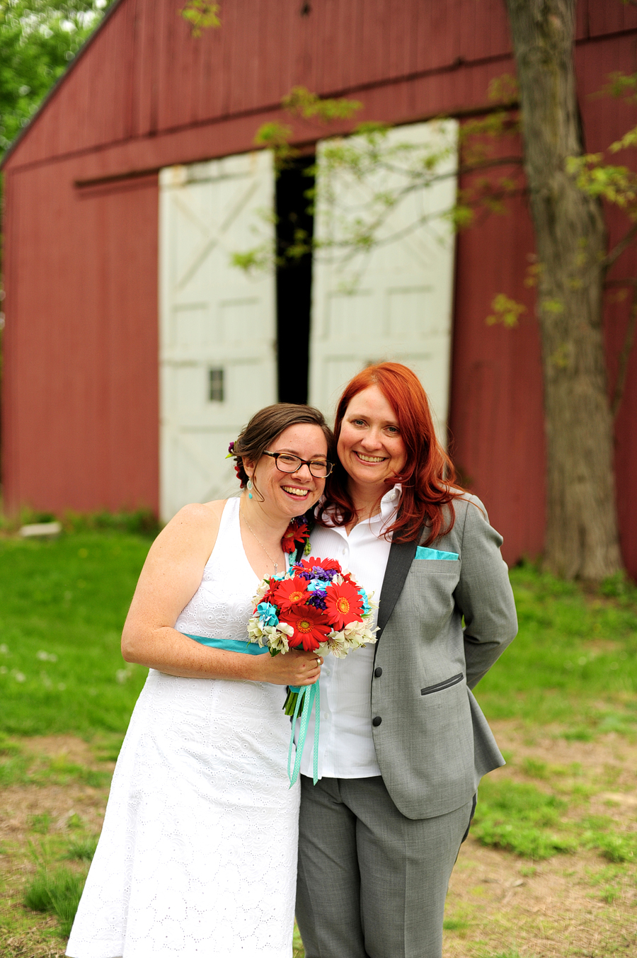 brides smiling near a red barn