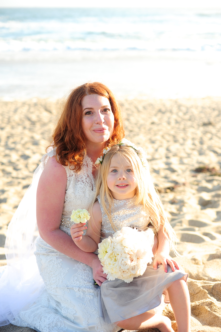 a redhead bride and her blonde daughter on the beach