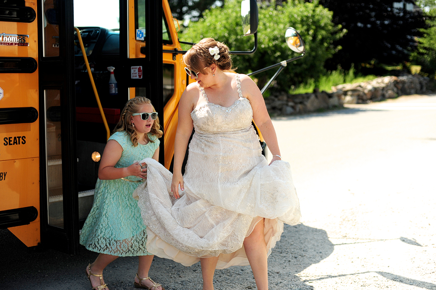 bride getting off a school bus with her flower girl in matching sunglasses
