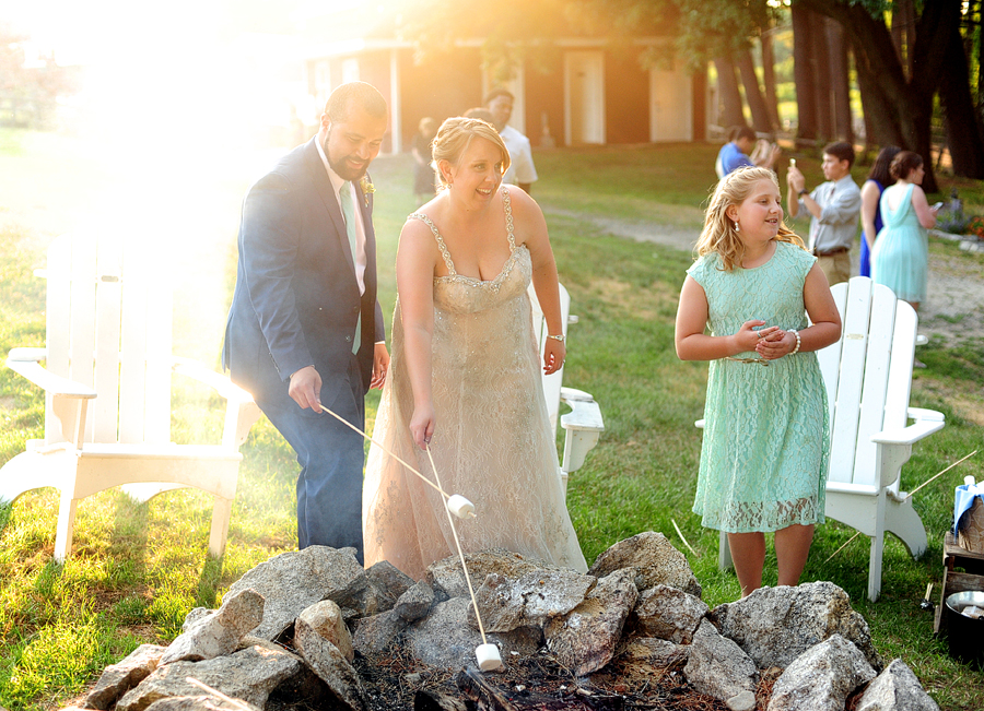 roasting s'mores at a fire pit at their wedding
