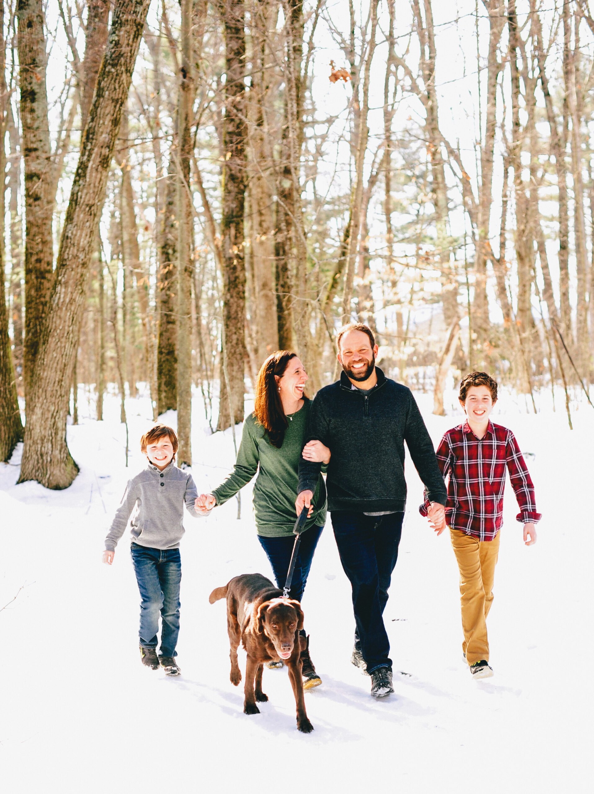 a happy family takes a walk through the maine woods with their dog