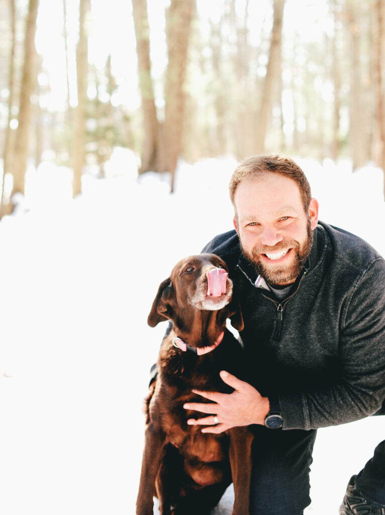 a man smiles alongside his elderly dog